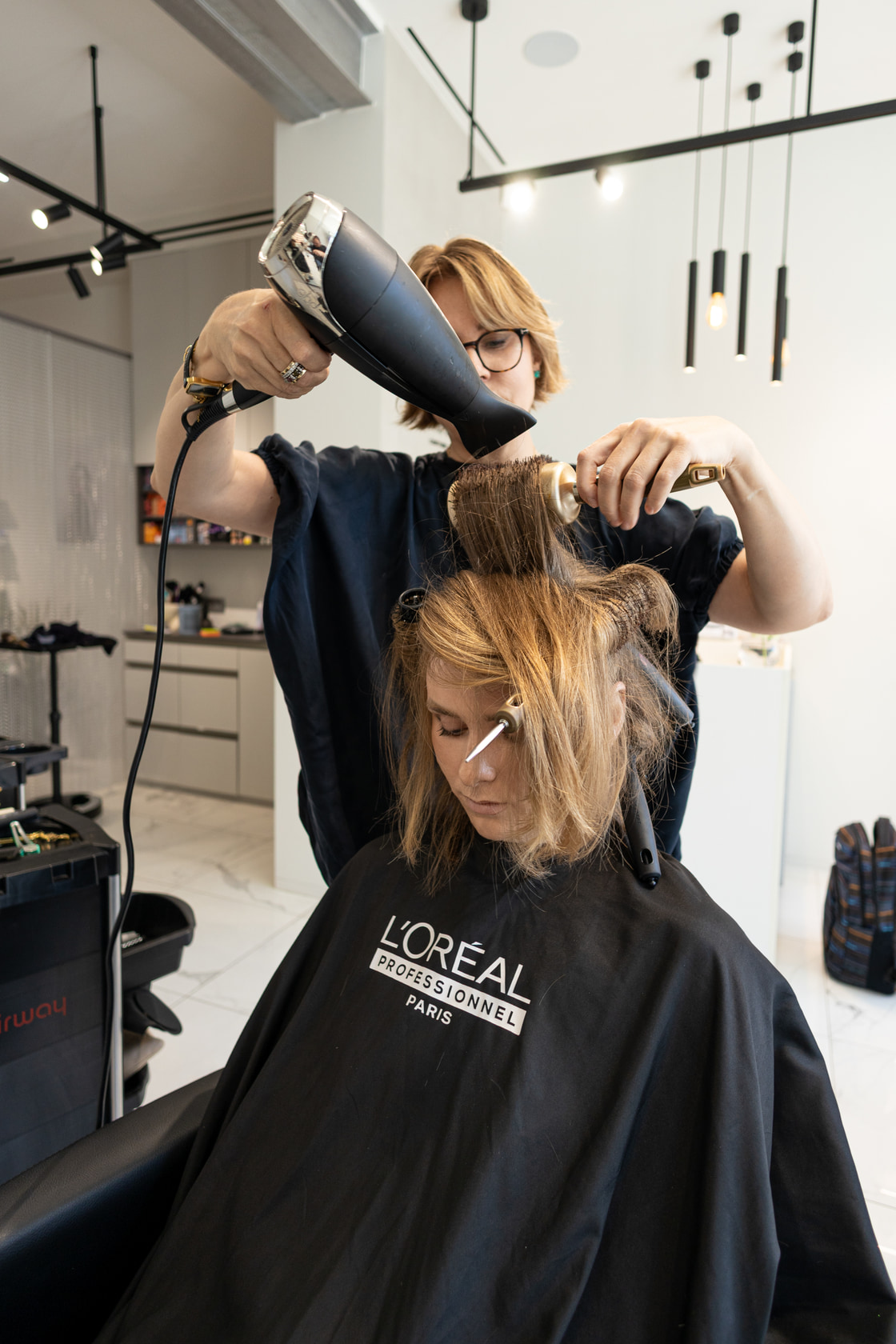 Hair styled with a dryer and round brush under the salon lights