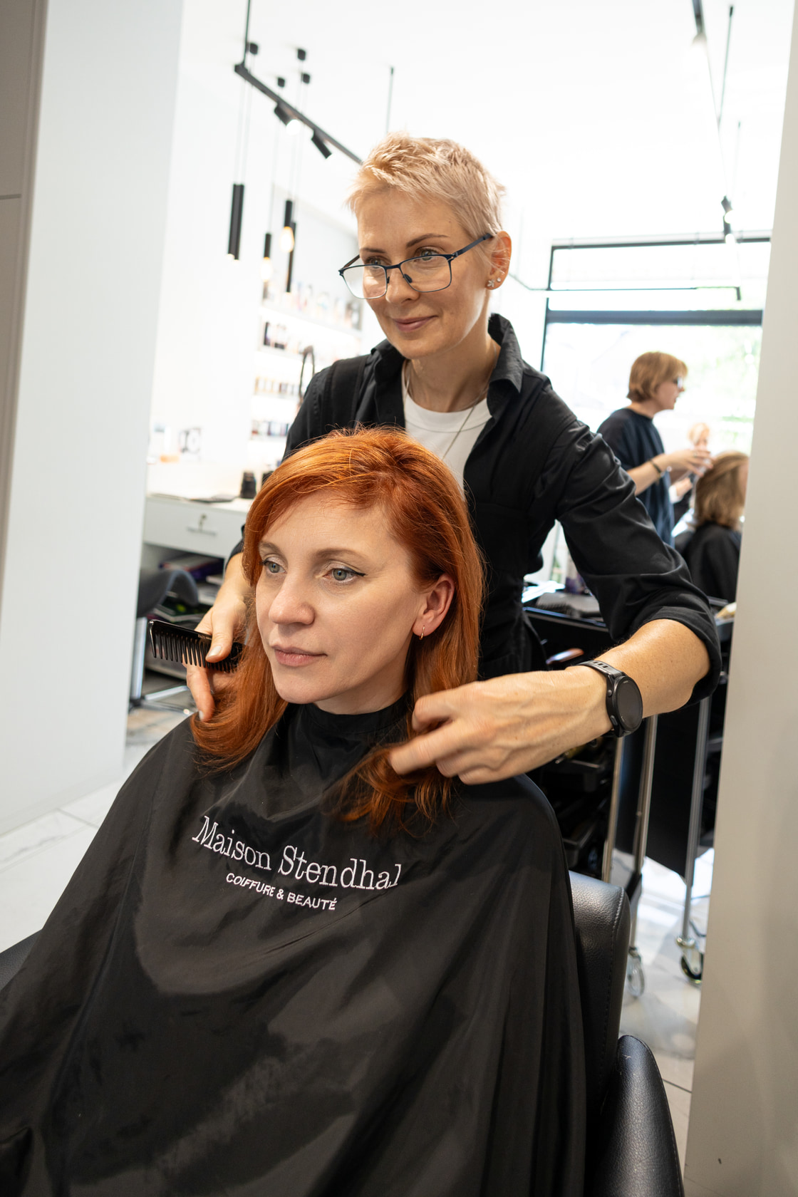 Stylist behind a client with freshly coloured red hair