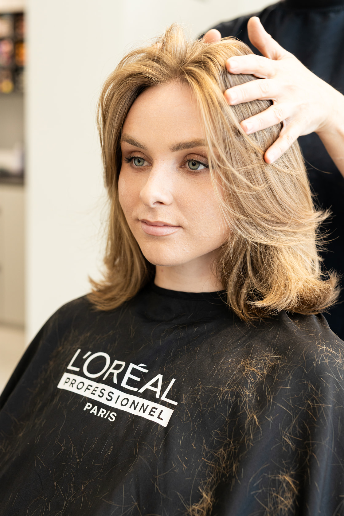 Client in a salon cape after a blow-dry, looking at the camera