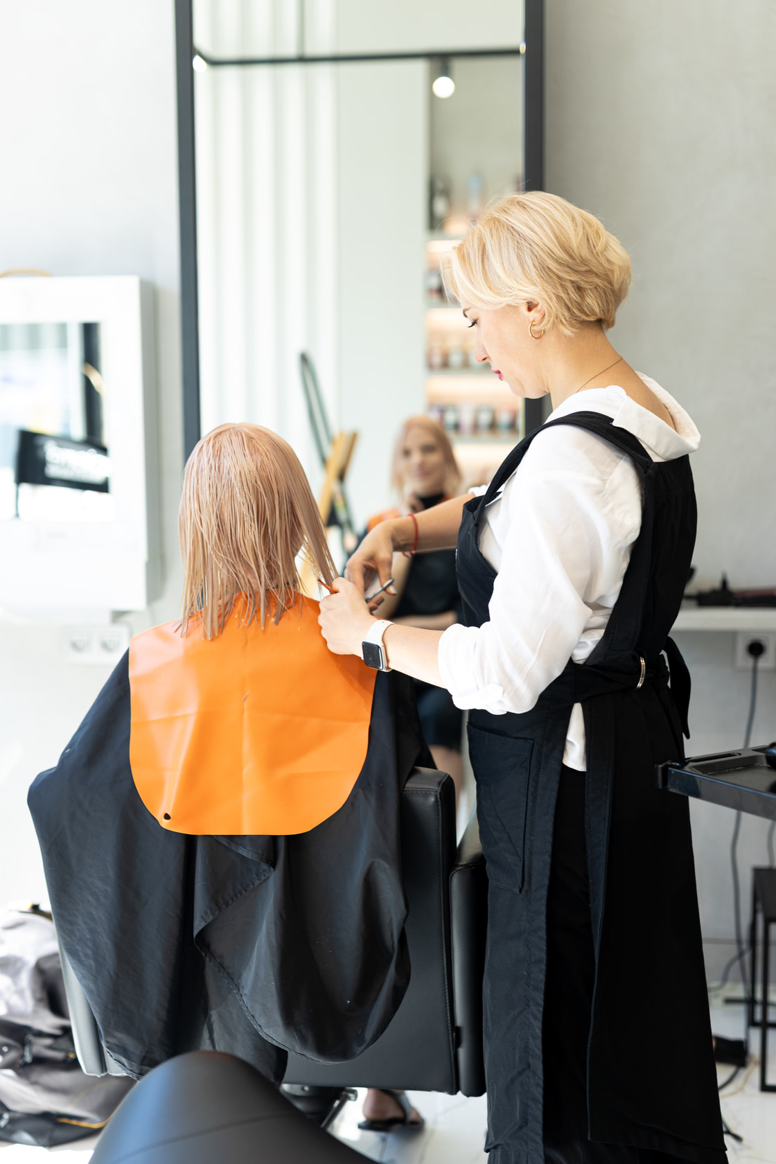 Stylist cutting hair, seen across the salon floor